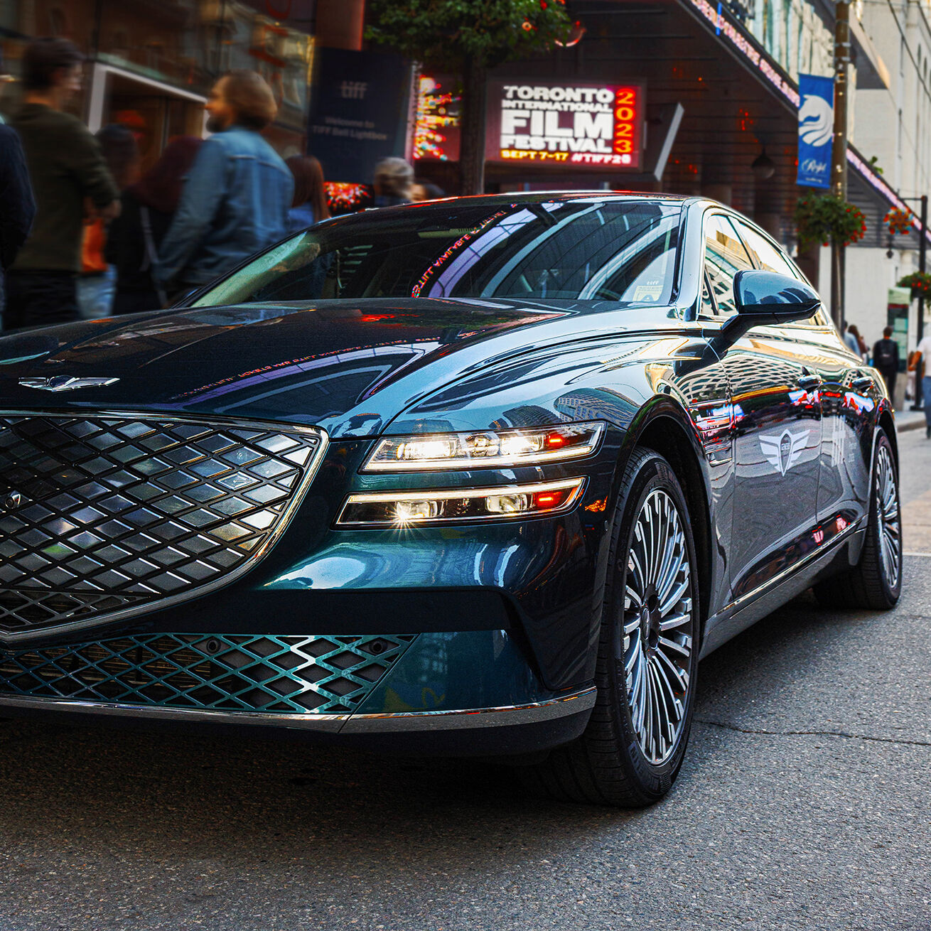 Side angle of Genesis Electrified G80 parked in front of theatre