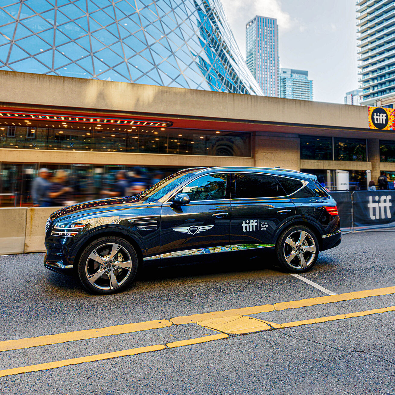 Genesis GV80 side view driving beside theatre