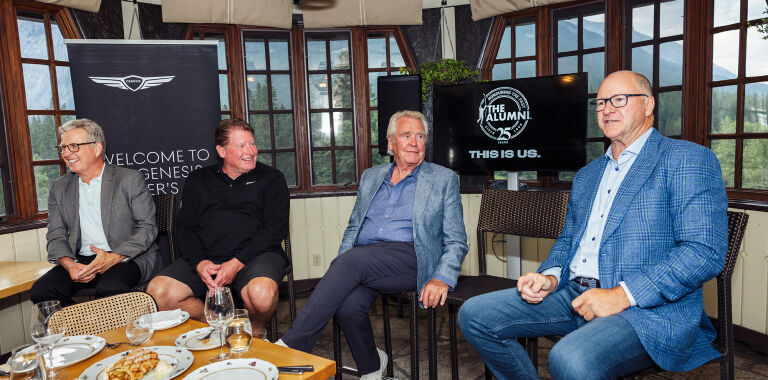Four NHL alumni sitting at a table with Genesis signage behind them 