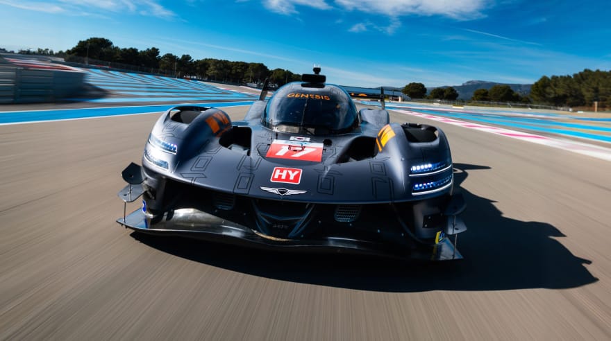 Front view of the GMR-001 hypercar racing on a circuit under a blue sky