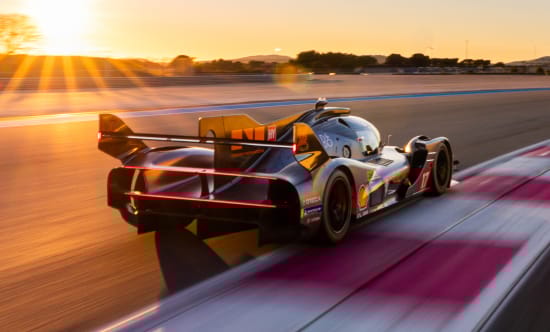 Rear three-quarter view of the GMR-001 hypercar racing at sunset