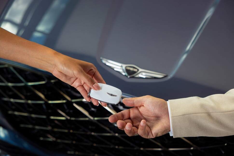 Genesis employee hands key to driver
