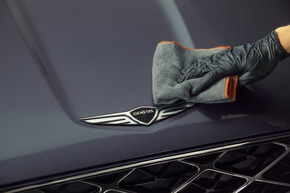 A Genesis Service Technician wipes the vehicle badge.