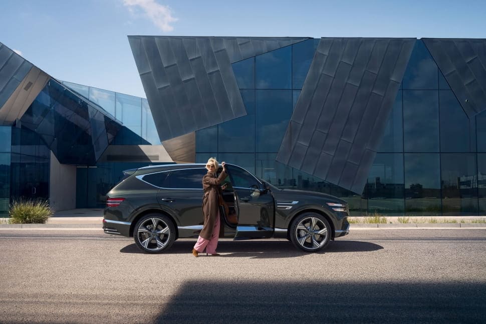 Woman stands outside Genesis GV80
