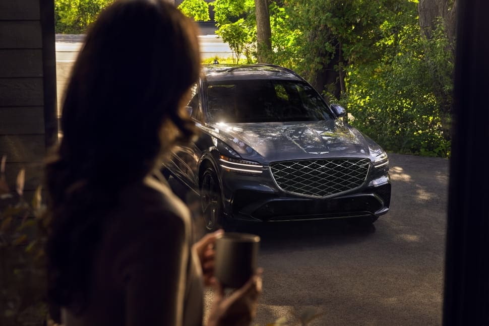 Woman looks at Genesis GV70 in driveway.