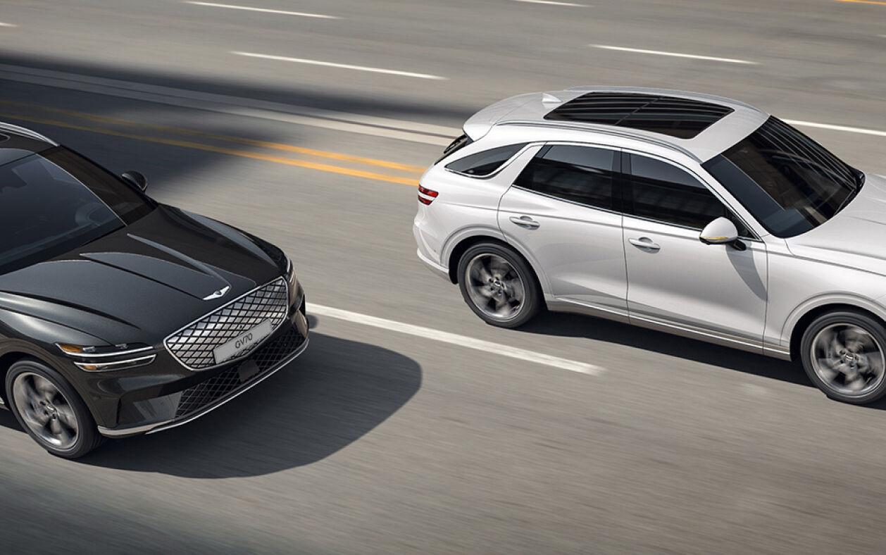 An angled aerial view of the Electrified GV70 overtaking a car on a highway.
