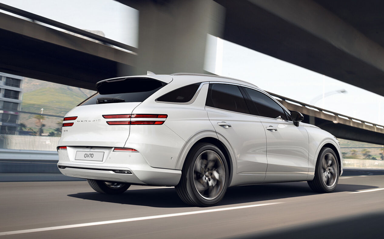 The Electrified GV70 is seen from behind as it drives on the highway.