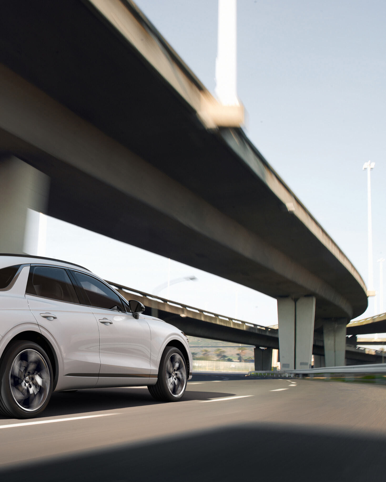The Electrified GV70 is seen from behind as it drives on the highway.