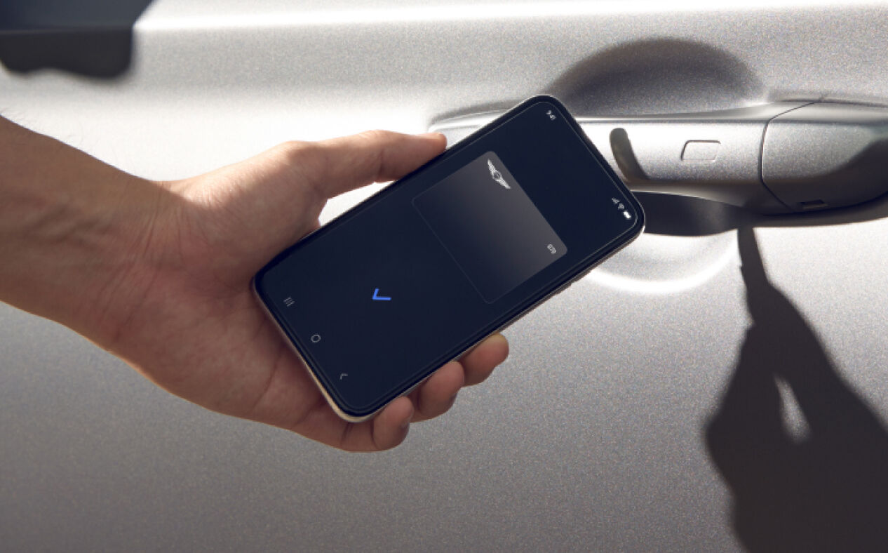 Close-up of a person's hand holding phone up to drivers handle Digital Key displayed on phone