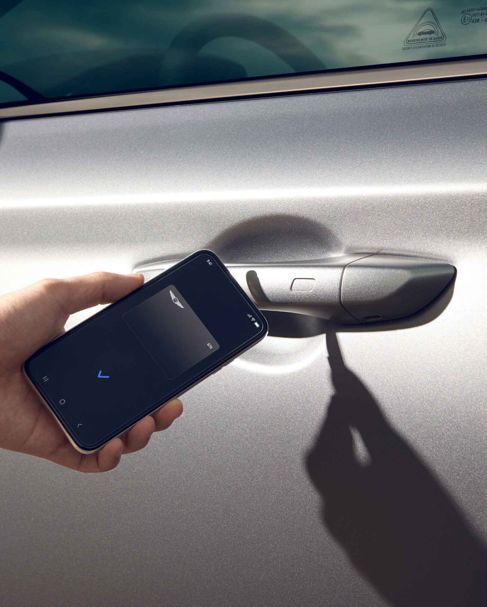 Close-up of a person's hand holding phone up to drivers handle Digital Key displayed on phone