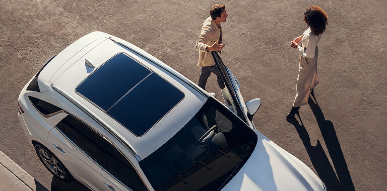 Two people outside a Genesis Vehicle