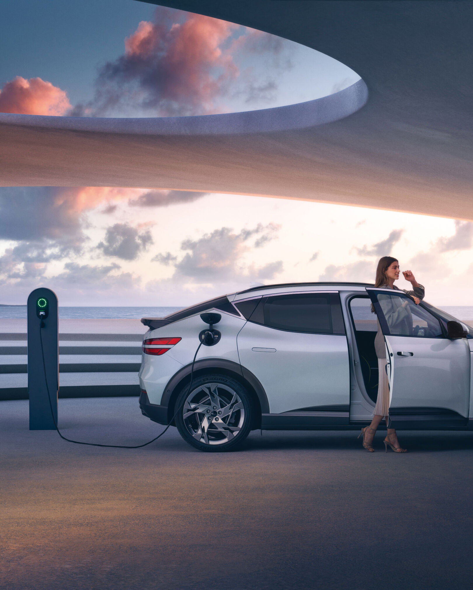 A side view of Uyuni White GV60 charging with woman infront of passenger door. 