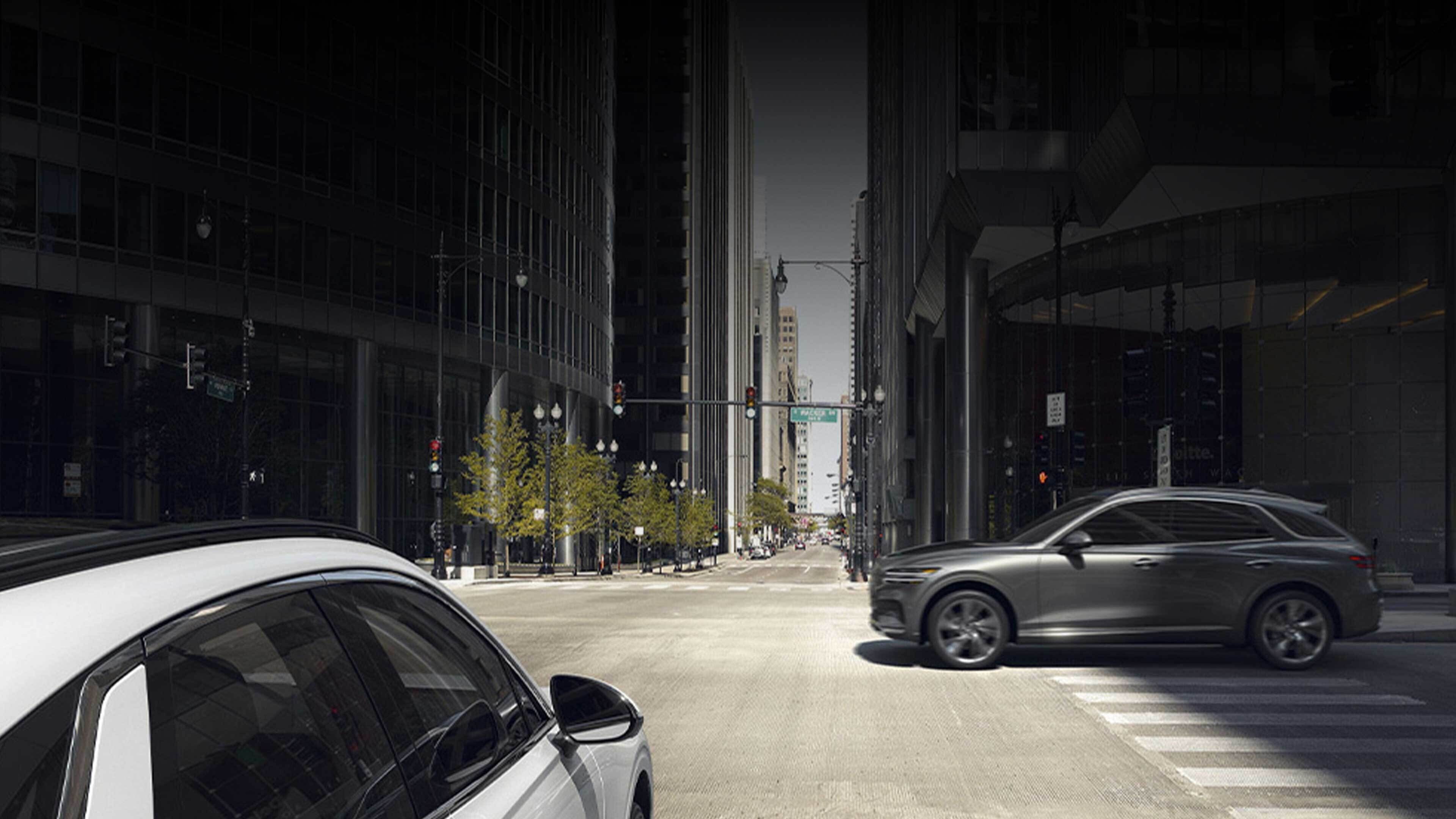 The Electrified GV70 is about to drive through a crossroads as another car speeds across.