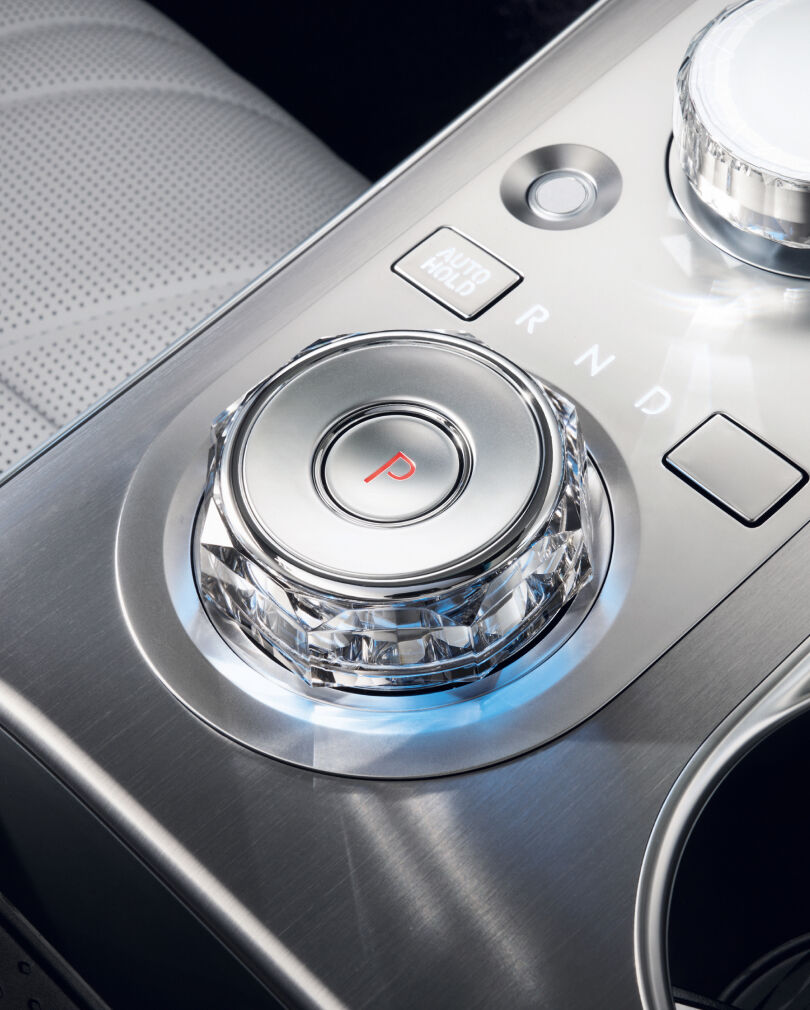 The electronic shift dial of the GV70, illuminated with a subtle blue light in the form of an octagonal crystal, is enlarged. The letter 'P' in red is written within the central circle.