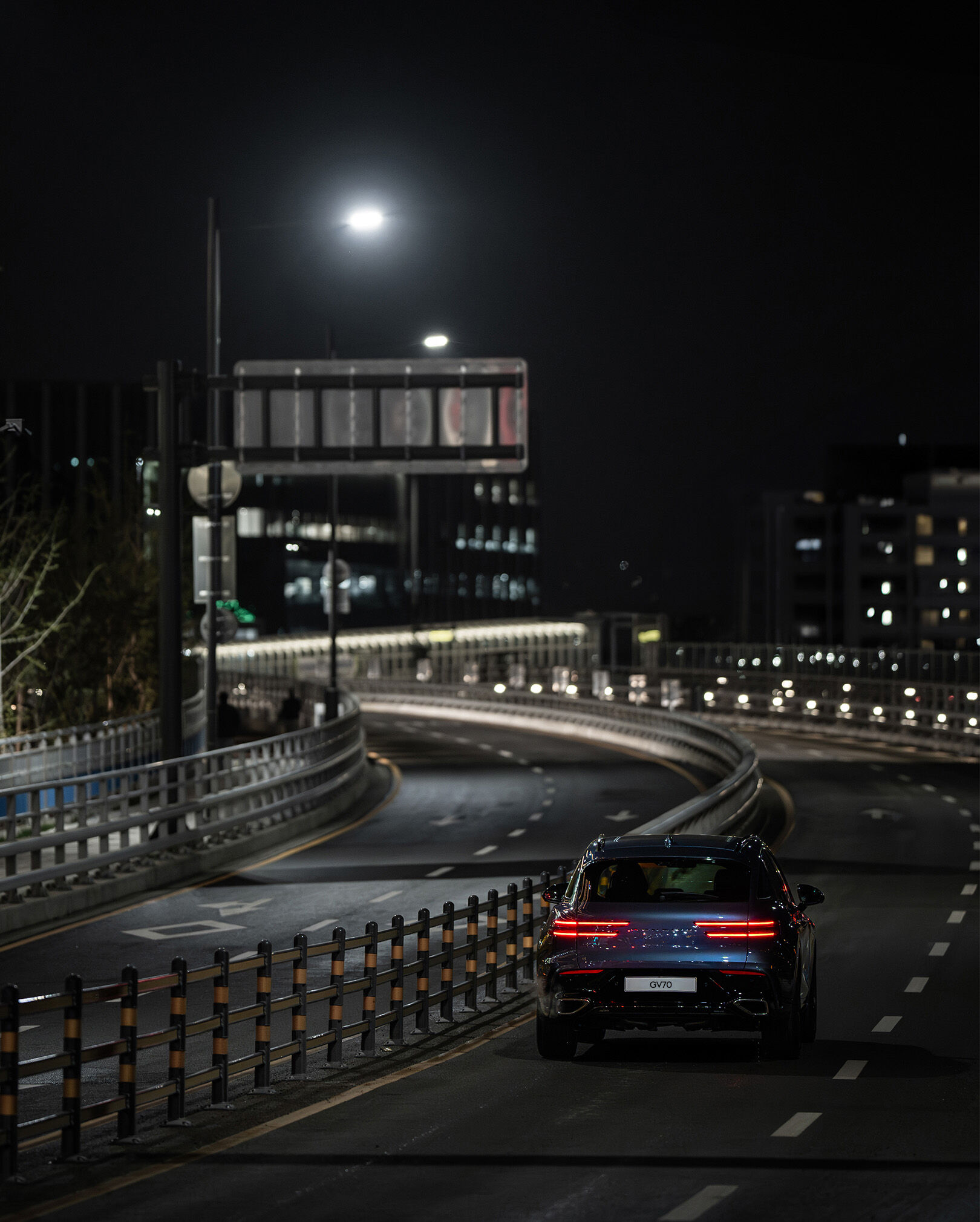 You can see the rear view of a Uni White GV70 driving on the highway.