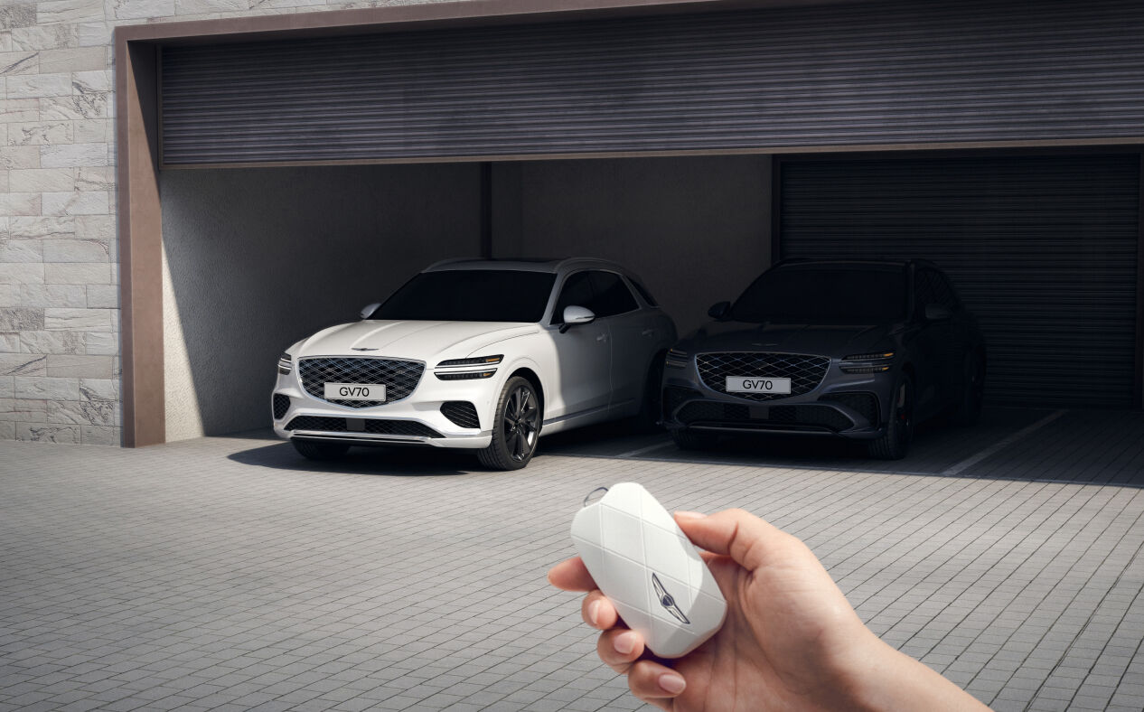 Outside the vehicle, the driver is using the smart key to park the GV70 in the garage.