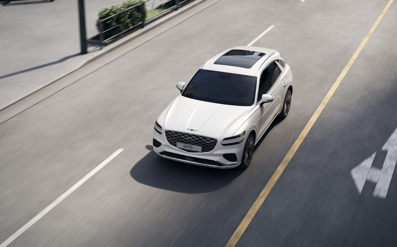 The GV70 is driving on the road, staying in its lane.