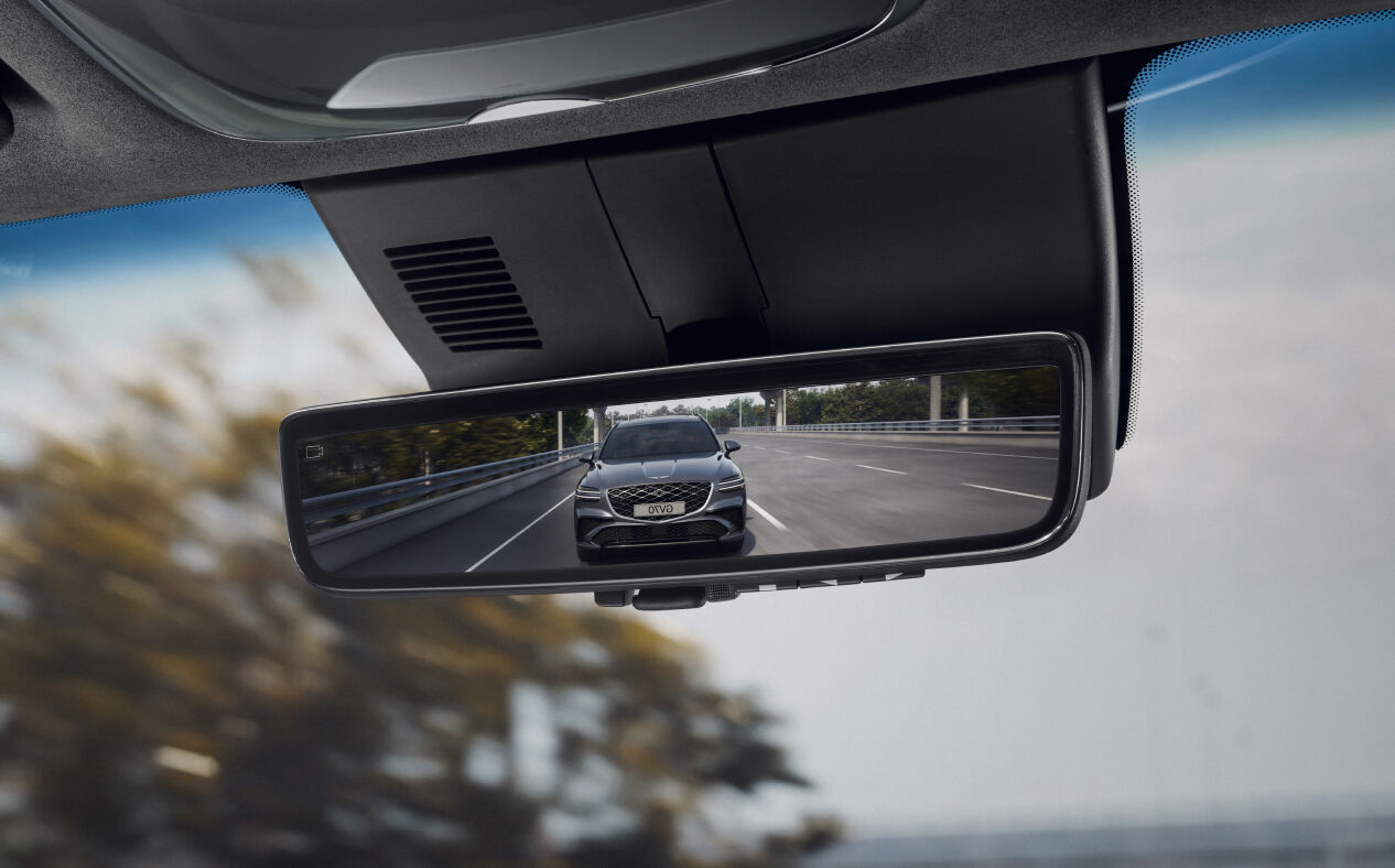 The front view of the car behind is reflected in the vehicle's rearview mirror.