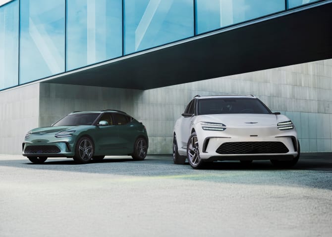 푸른색 통창이 보이는 건물 아래로 정차된 두 대의 GV60 차량이 보입니다.