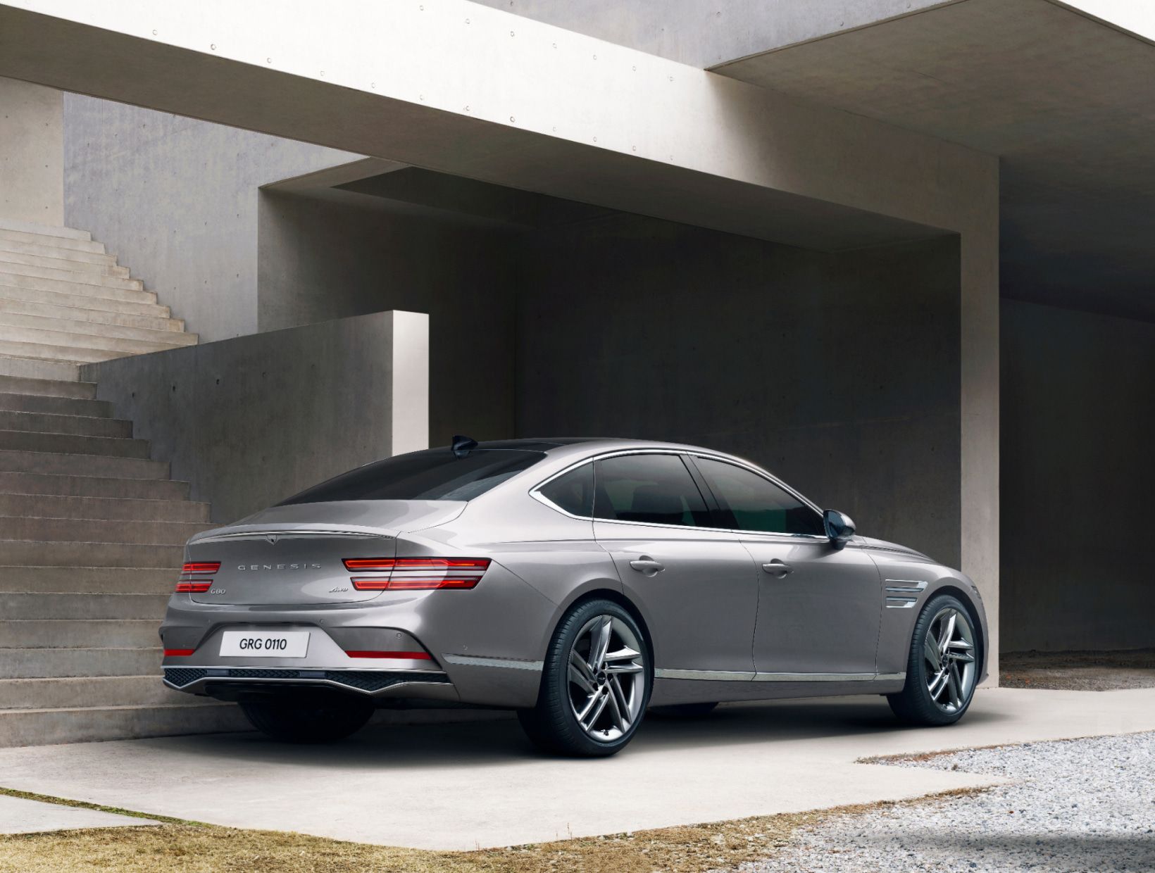 오른쪽 후면이 보이는 G80 차량이 콘크리트 구조물이 있는 실외 공간에 정차해 있습니다.