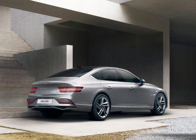 오른쪽 후면이 보이는 G80 차량이 콘크리트 구조물이 있는 실외 공간에 정차해 있습니다.