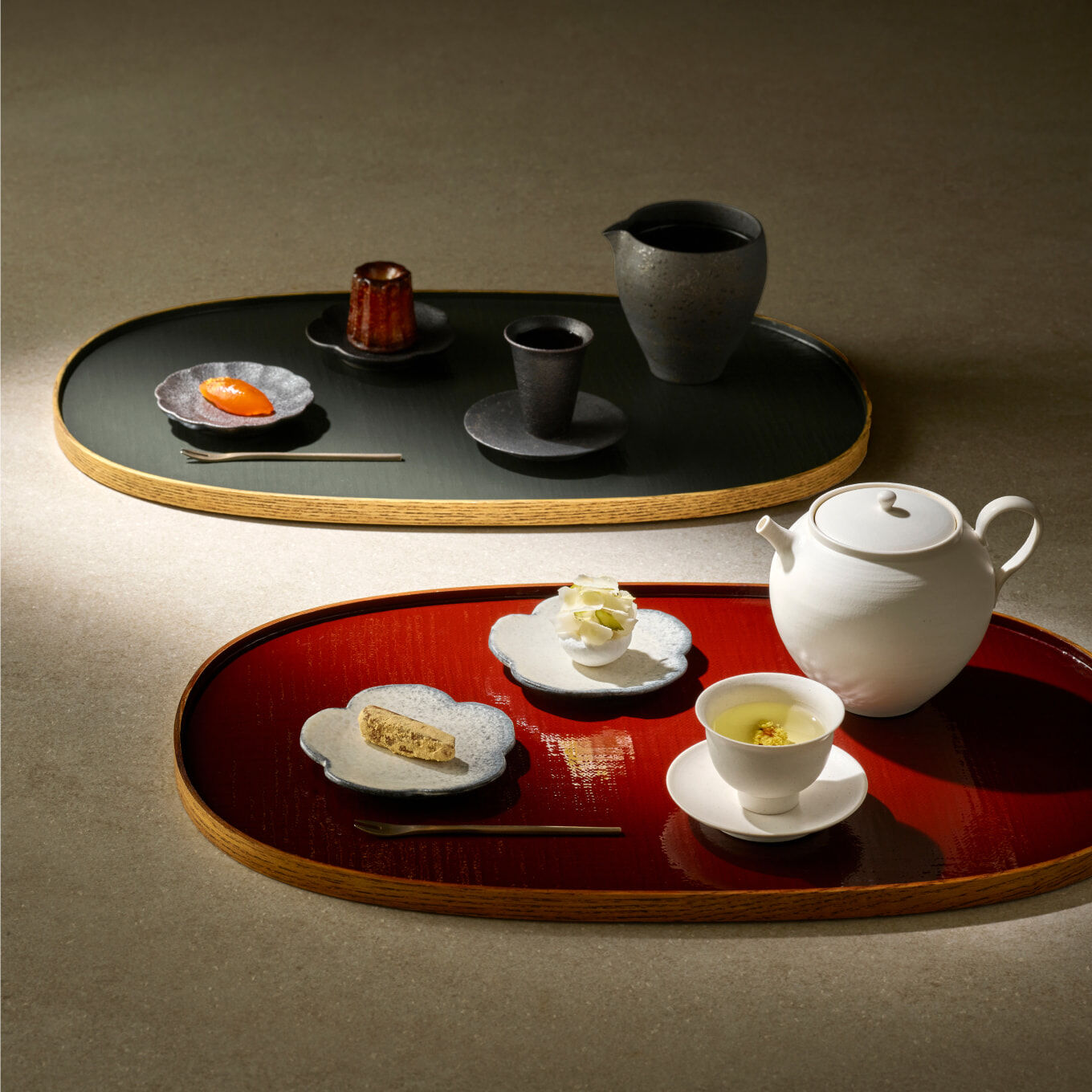 A traditional white and black teacups on a plate, with luxurious refreshments on a flower-shaped saucer.