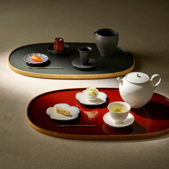 A traditional white and black teacups on a plate, with luxurious refreshments on a flower-shaped saucer.