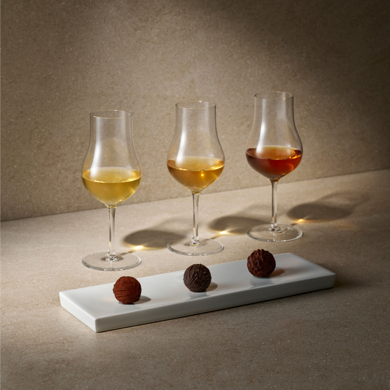 A whisky glass accompanied by three bite-sized small bites, artfully aligned in harmony.