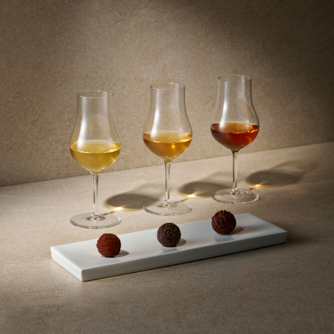 A whisky glass accompanied by three bite-sized small bites, artfully aligned in harmony.