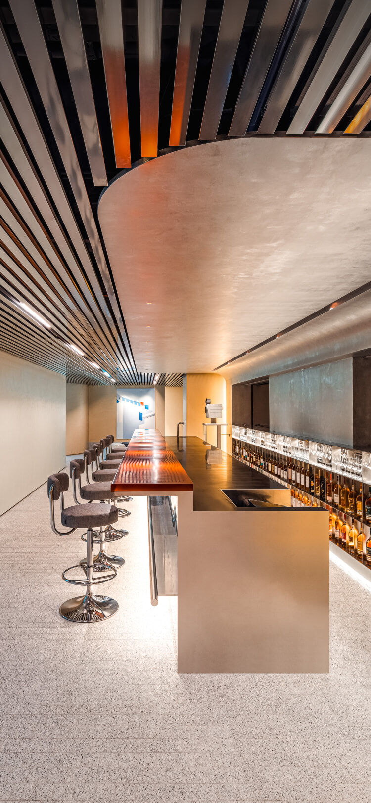 A side view of a whiskey and wine bar interior, where curved and linear ceiling designs blend harmoniously within an elegant, upscale ambiance.