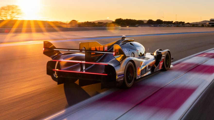Rear three-quarter view of the GMR-001 hypercar racing at sunset