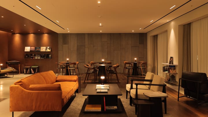 해비치 제주 오너스 G 라운지에 정면으로 소파와 커피 테이블이 위치하며, 뒤쪽에는 크고 작은 테이블이 보입니다. 