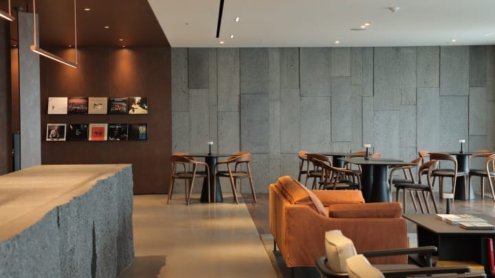 해비치 제주 오너스 G 라운지에 여러 테이블이 있으며, 벽 디스플레이 선반에 올려져 있는 LP가 보입니다. 