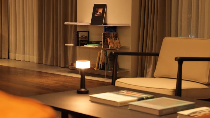 해비치 제주 오너스 G 라운지에 커피 테이블 가운데는 스탠드 조명이 켜져있고 뒤쪽에는 책장과 몇 권의 책들이 보입니다. 