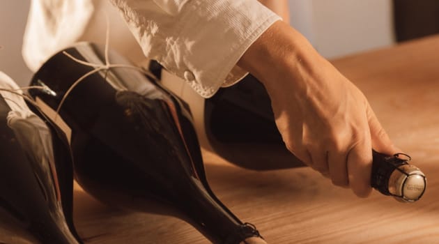 눕혀진 와인병을 손으로 잡는 이미지