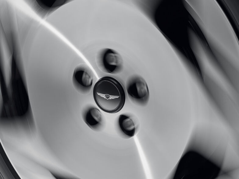 The Genesis logo is clearly visible in the center as the floating wheel cap is spinning.