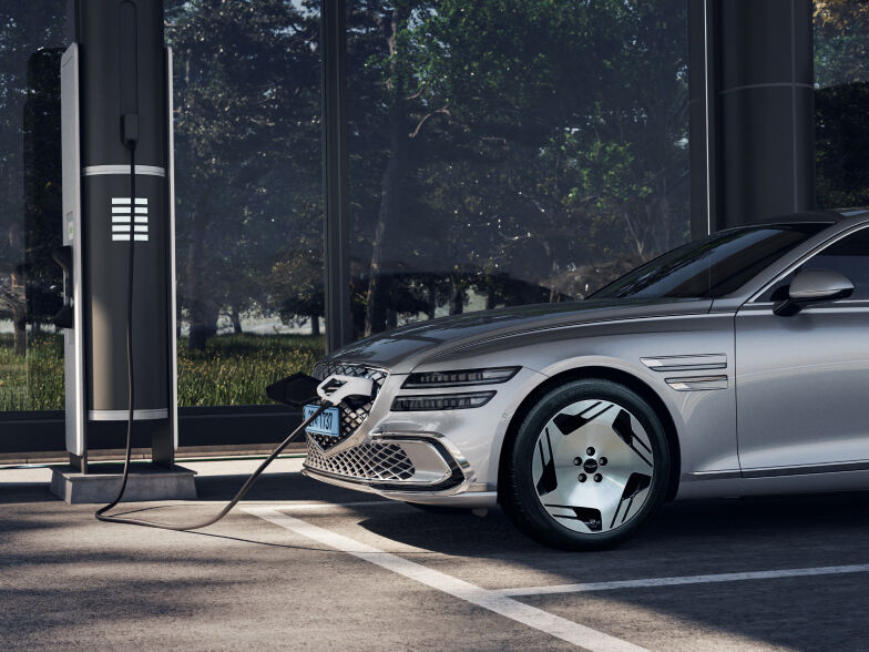 An Electrified G80 is parked at an outdoor charging station. It is connected to the charger and charging.