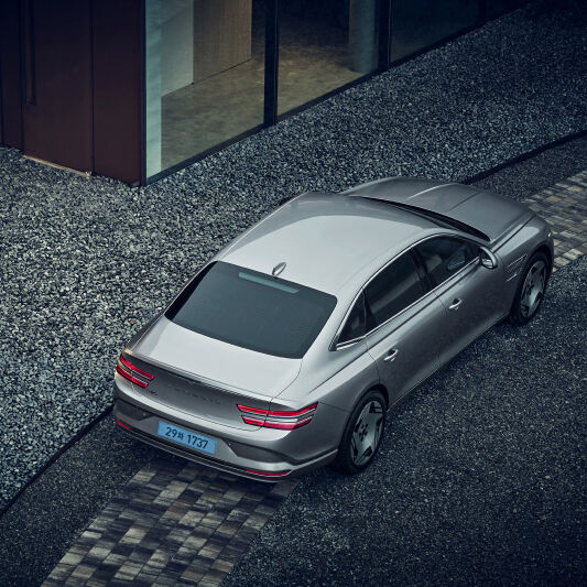 A vertical view of the rear of an Electrified G80 parked on the road. 
