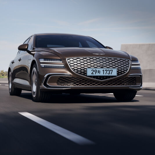 A Brooklyn Brown colored Electrified G80 is seen on the road.