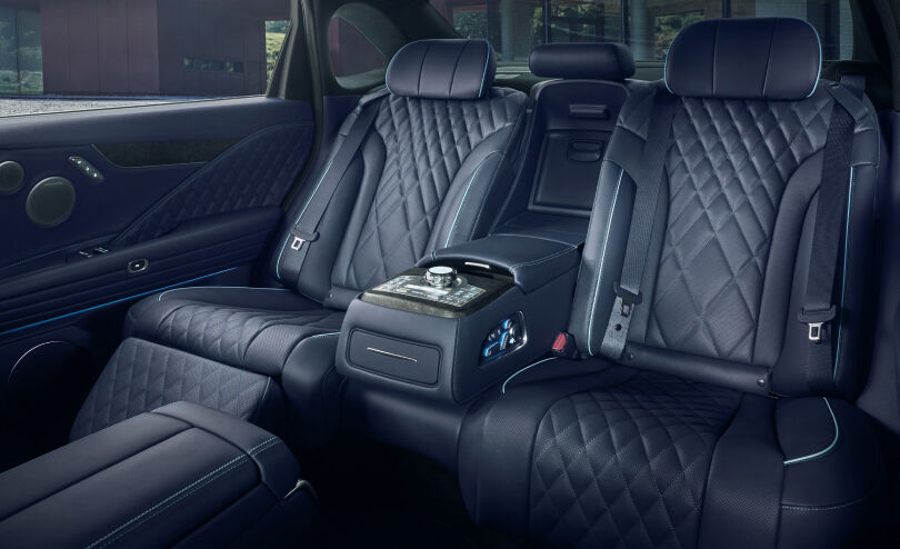 The view from the front seat shows the spacious rear of the car, with a center armrest with a bright controller and luxurious quilted leather seats.