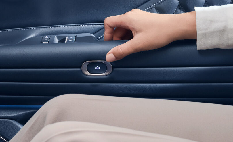 View the door trim button on the rear passenger door and the hand trying to press it.