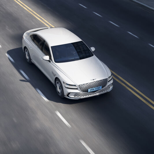 Uyuni white colored Electrified G80 is driving on the road.