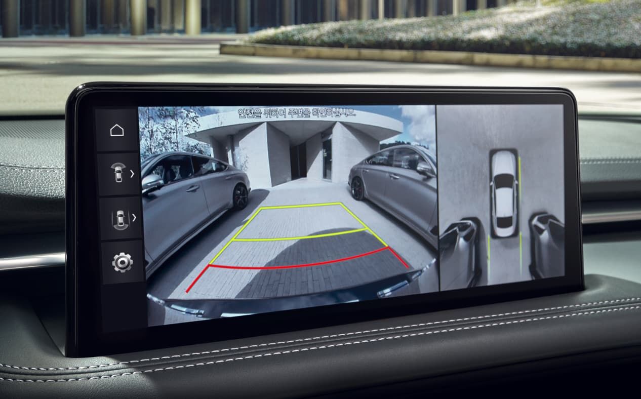 The Uyuni White G70 is seen exiting a parking lot. The infotainment display shows the surroundings.