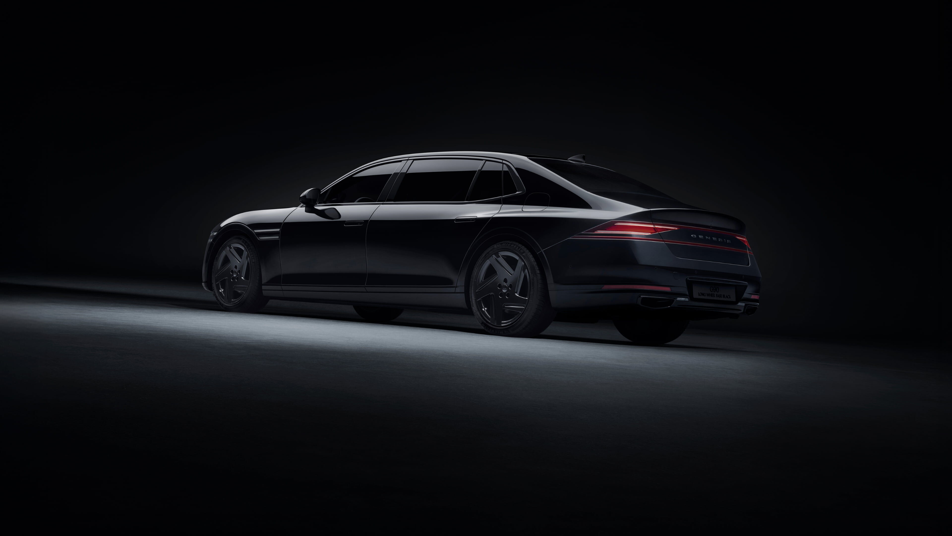 A rear/side view of the G90 Long Wheel Base Black long body, parked on illuminated ground in a dark space.