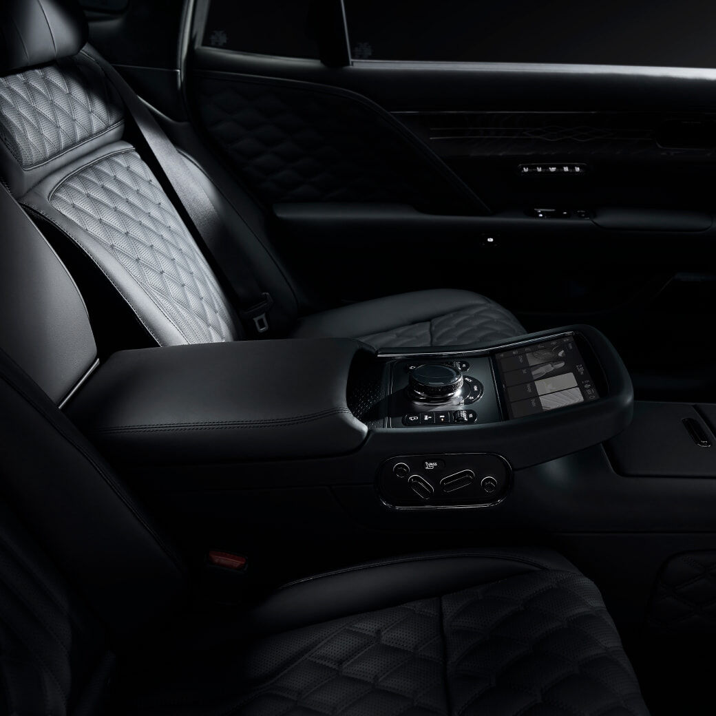 From a side perspective, the rear black leather seats, along with the digital control panel and various function buttons on the center console, are visible.