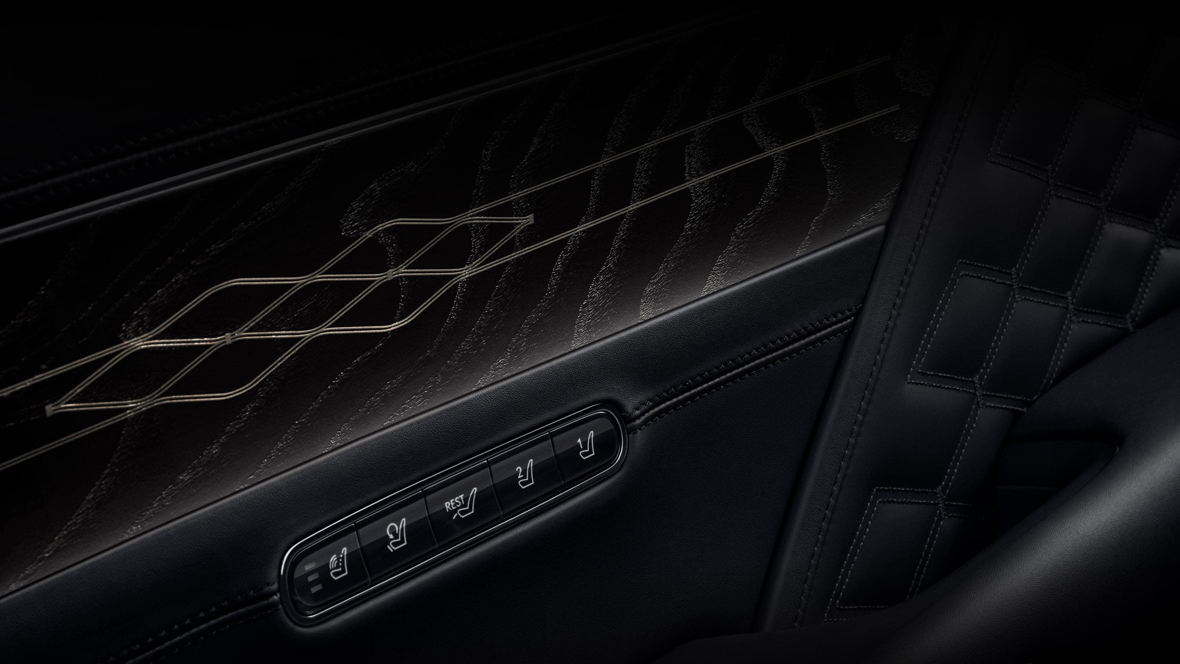 A close-up view of the black ash wood material applied to the interior door, along with the seat adjustment buttons. The surface features a natural wood grain texture overlaid with black color and an elegant pattern.