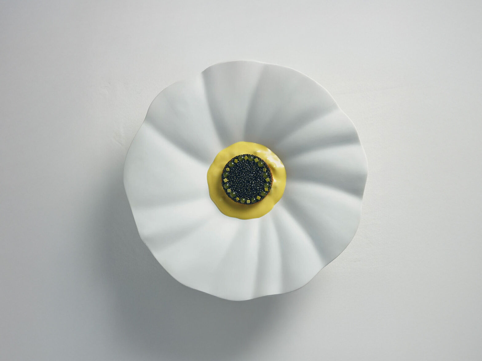 A Michelin-starred restaurant dish, specially prepared for G90 Long Wheel Base Black owners, is displayed. A luxurious black caviar dish with yellow sauce is plated on a white dish resembling a blooming flower.