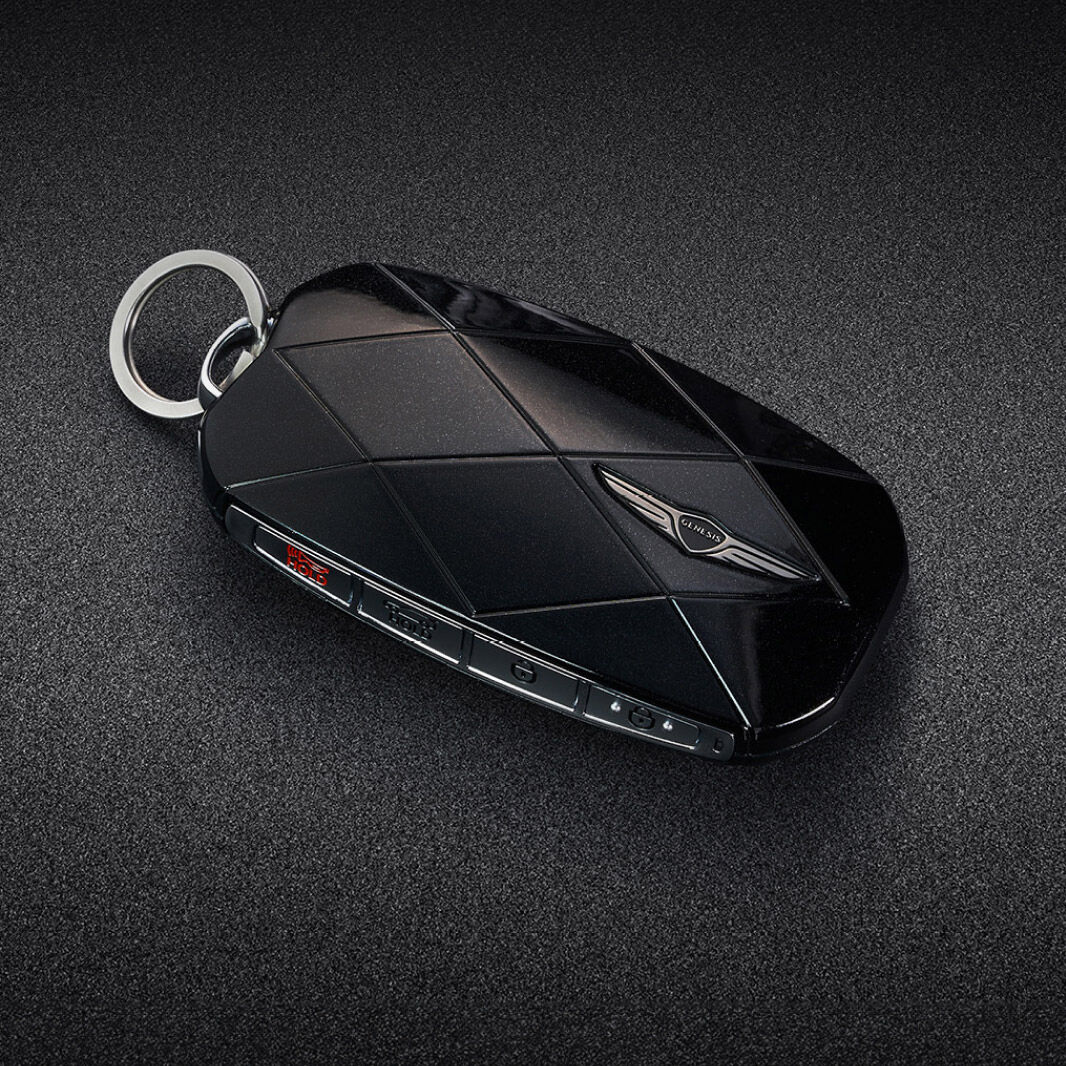 The black smart key is adorned with a Genesis emblem and diamond pattern lines.