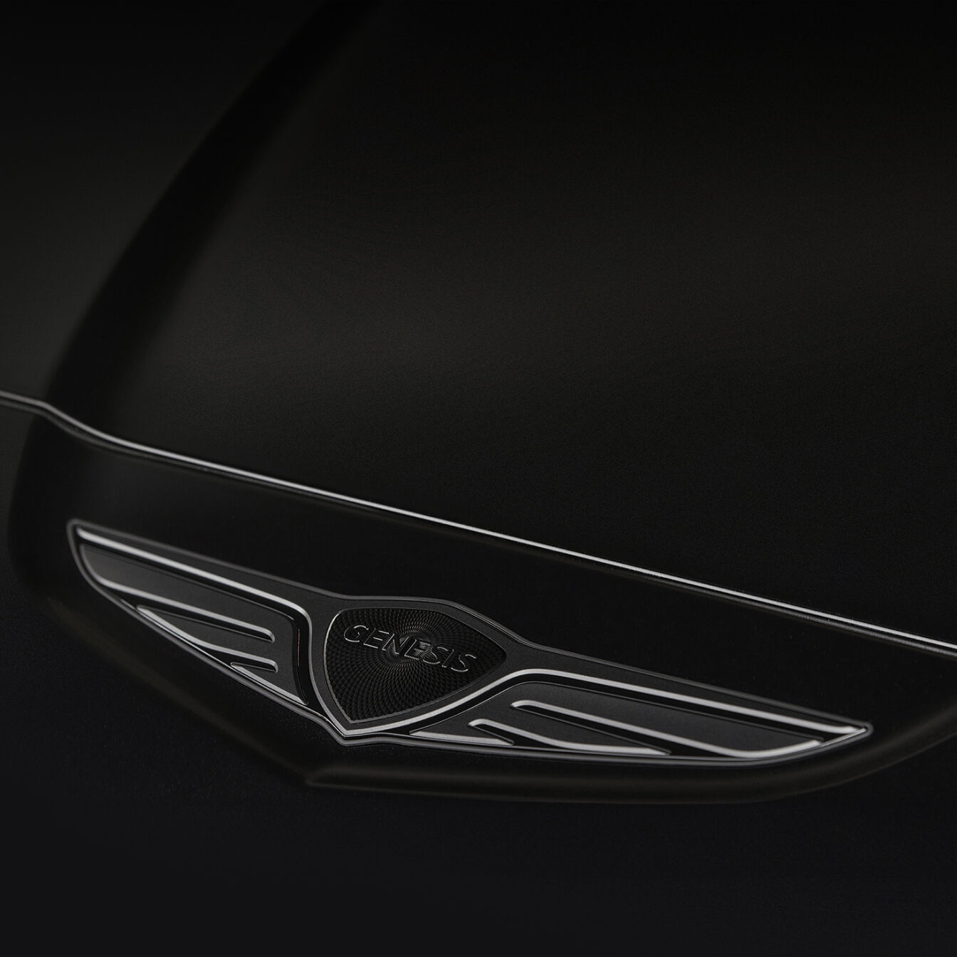 In the center of the wing-shaped design, the Genesis logo, written in black chrome material, is visible.