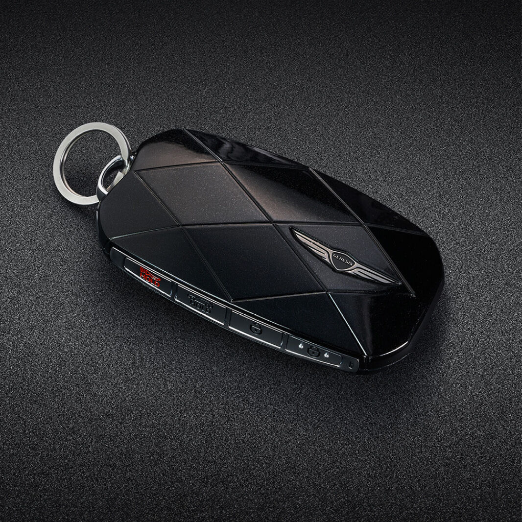 The black smart key is adorned with a Genesis emblem and diamond pattern lines.
